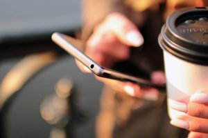 Girl holding a coffee with phone in the other hand