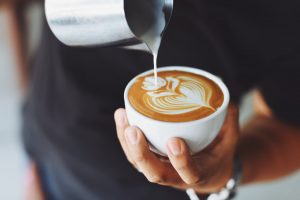 Person pouring cream on coffee